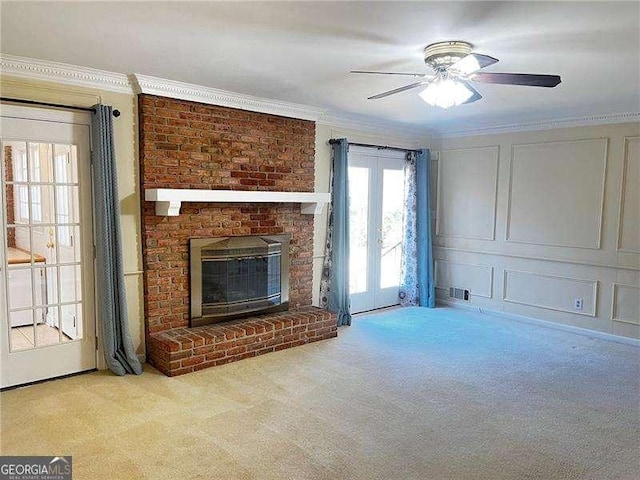 unfurnished living room with a decorative wall, carpet floors, a fireplace, visible vents, and crown molding