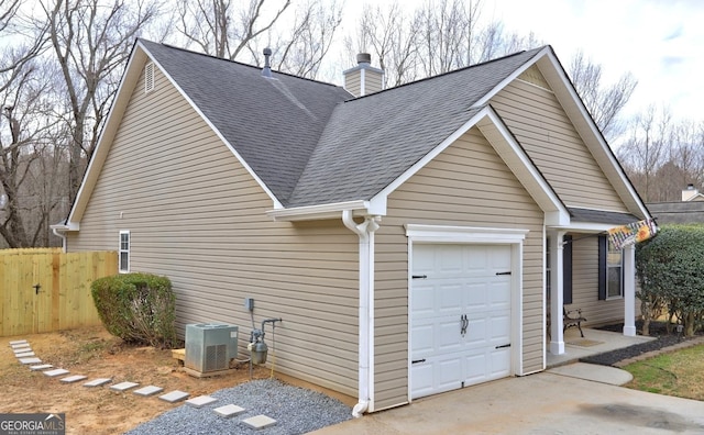 view of side of property with a garage, central AC, fence, roof with shingles, and a chimney