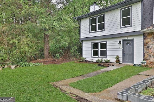 view of front facade with stone siding, a chimney, and a front lawn