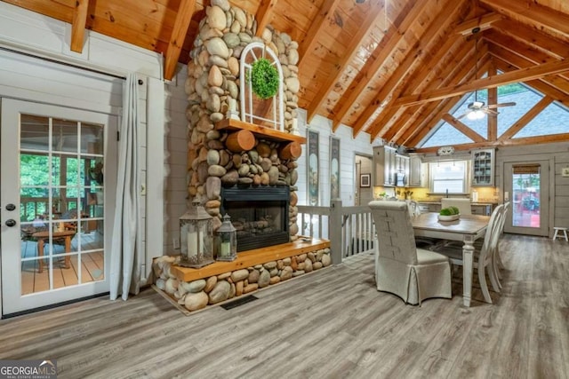 dining space featuring vaulted ceiling with beams, a fireplace, and wood finished floors