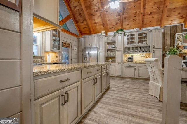 kitchen with vaulted ceiling with beams, wooden ceiling, light wood-style floors, stainless steel refrigerator with ice dispenser, and glass insert cabinets