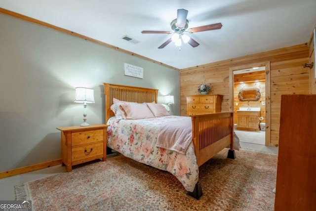 bedroom with visible vents, ensuite bathroom, ceiling fan, wooden walls, and baseboards