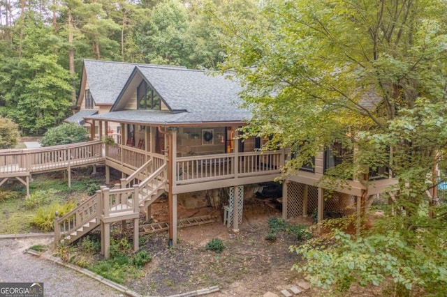 view of front of property with a shingled roof, stairway, and a deck