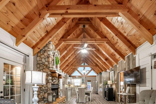 interior space with high vaulted ceiling, a stone fireplace, wooden ceiling, and beam ceiling