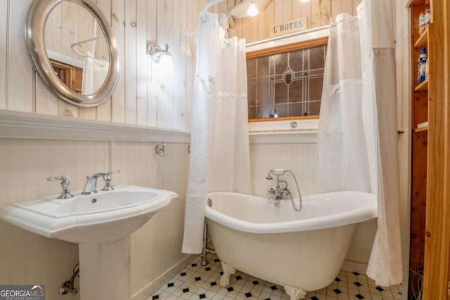 full bath featuring a soaking tub and a sink