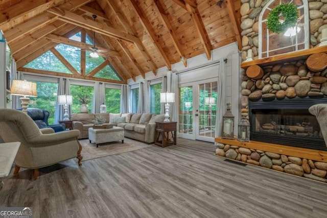 sunroom featuring lofted ceiling with beams, ceiling fan, visible vents, and a stone fireplace