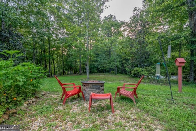 view of yard with a fire pit and a view of trees