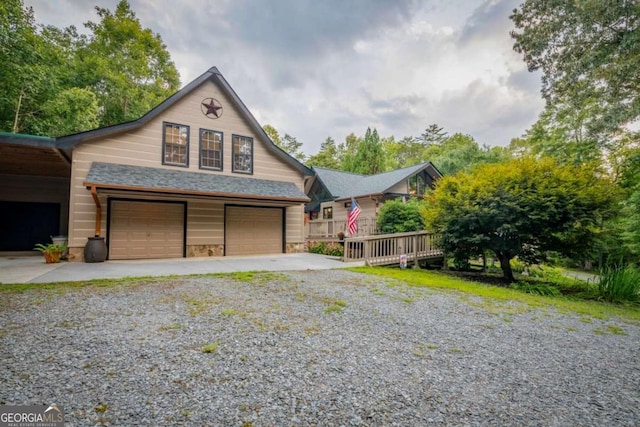 rustic home with driveway, stone siding, and roof with shingles