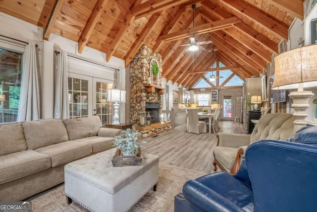 living room featuring wooden ceiling, beamed ceiling, a stone fireplace, french doors, and high vaulted ceiling