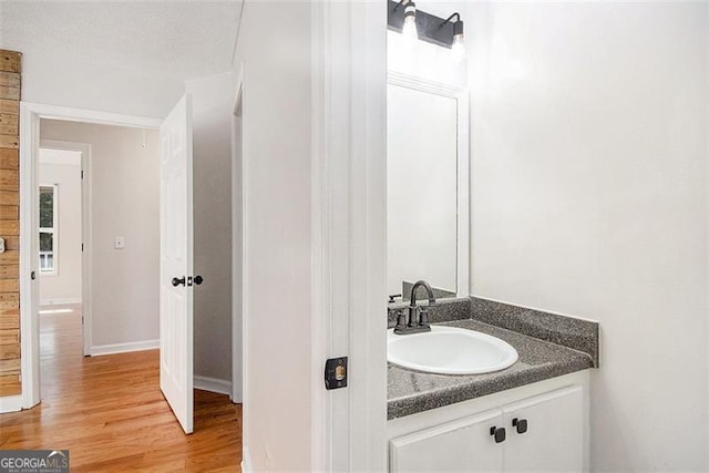 bathroom with wood finished floors, vanity, and baseboards