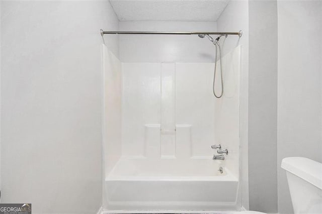 bathroom featuring a textured ceiling, shower / washtub combination, and toilet