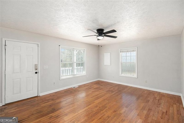 interior space featuring visible vents, baseboards, a ceiling fan, wood finished floors, and a textured ceiling