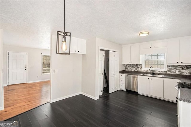 kitchen featuring a sink, dark countertops, decorative backsplash, and dishwasher