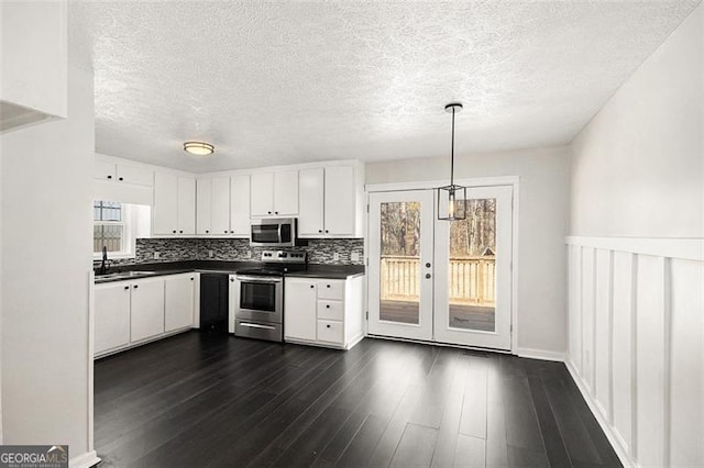 kitchen with white cabinets, dark countertops, dark wood-style floors, appliances with stainless steel finishes, and a sink