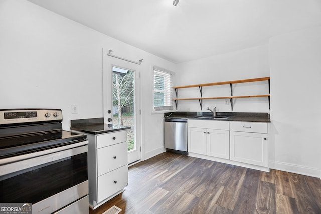 kitchen featuring dark countertops, dark wood-style floors, stainless steel appliances, open shelves, and a sink