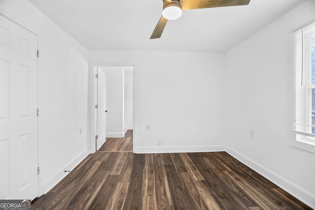 empty room featuring a wealth of natural light, ceiling fan, baseboards, and dark wood-style flooring