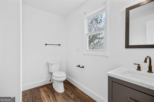 half bath featuring toilet, baseboards, wood finished floors, and vanity