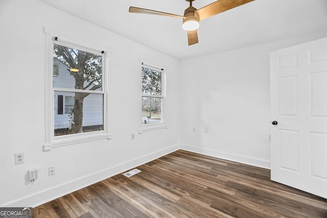 spare room featuring a ceiling fan, visible vents, baseboards, and dark wood-style flooring