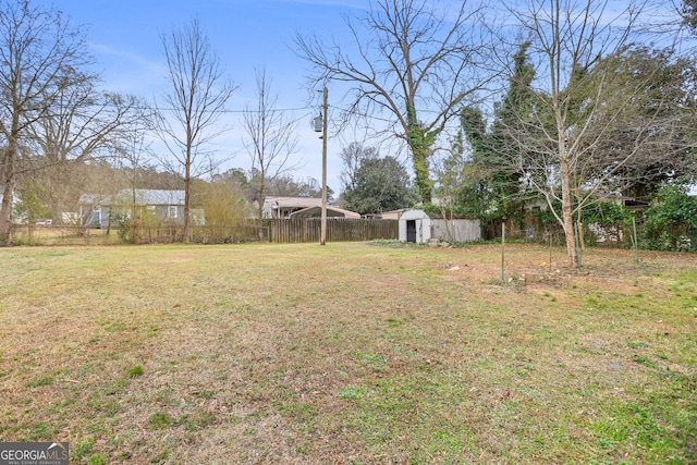 view of yard with a shed, fence, and an outbuilding