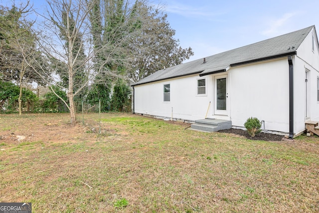 rear view of house with entry steps and a yard