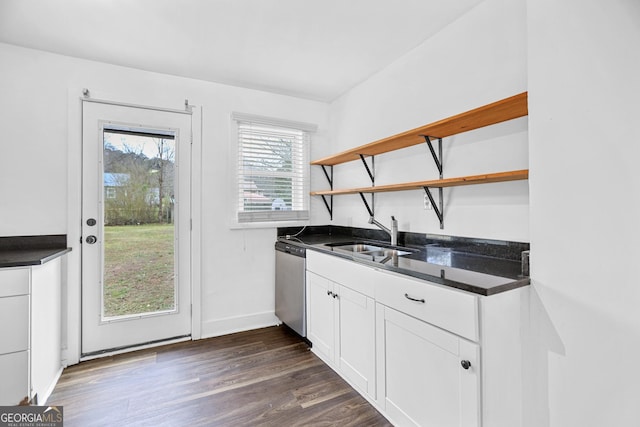 kitchen featuring dark wood-type flooring, a sink, stainless steel dishwasher, open shelves, and dark countertops