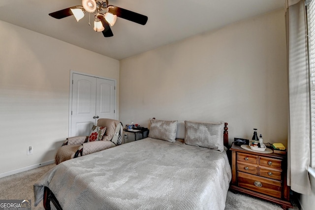 carpeted bedroom featuring a closet, baseboards, and ceiling fan
