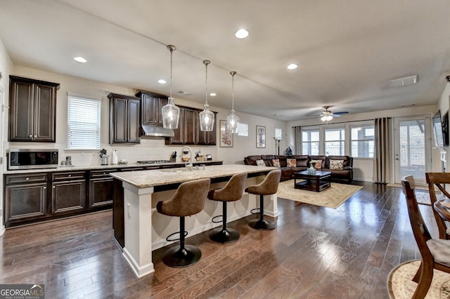 kitchen featuring a wealth of natural light, stainless steel appliances, a kitchen breakfast bar, and under cabinet range hood