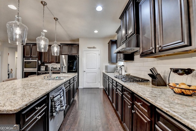 kitchen with light stone counters, a sink, stainless steel appliances, tasteful backsplash, and under cabinet range hood