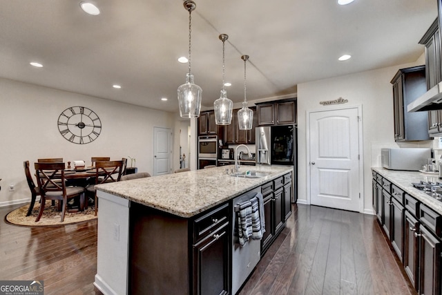 kitchen with a sink, dark wood-type flooring, stainless steel appliances, recessed lighting, and an island with sink