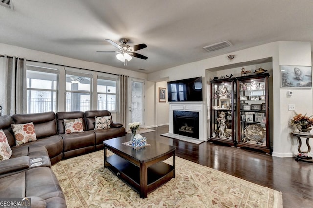 living room with baseboards, a ceiling fan, wood finished floors, and visible vents