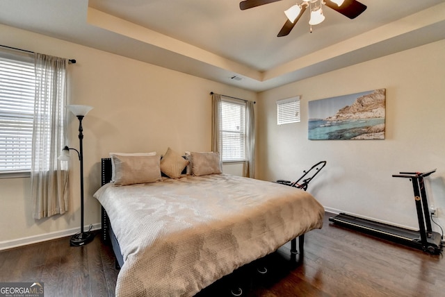 bedroom featuring visible vents, baseboards, a tray ceiling, and dark wood-style floors