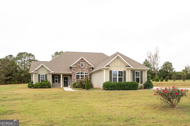 view of front facade with stone siding, a shingled roof, a front lawn, and board and batten siding