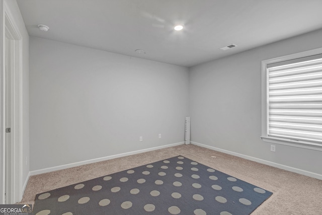spare room with plenty of natural light, carpet flooring, visible vents, and baseboards