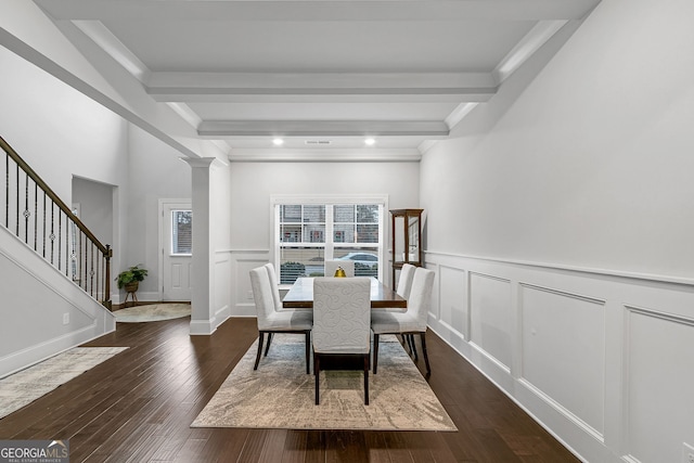dining area featuring dark wood-style flooring, beam ceiling, a decorative wall, and ornate columns