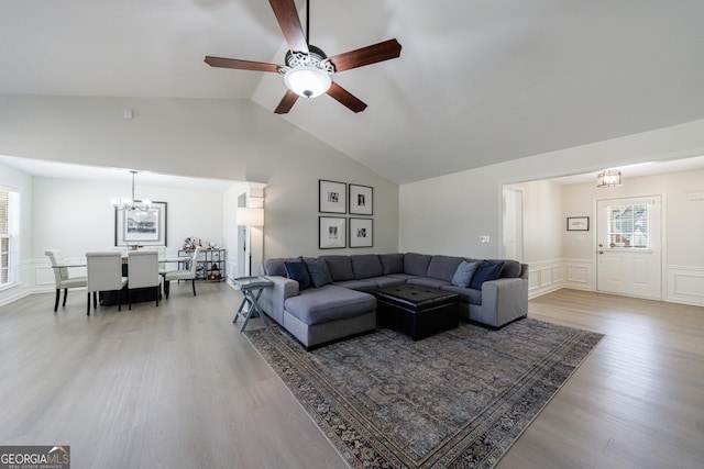 living room with a wealth of natural light, vaulted ceiling, a decorative wall, and wood finished floors