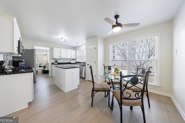 dining space with light wood finished floors, a ceiling fan, and baseboards