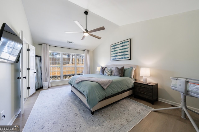 bedroom with visible vents, a ceiling fan, vaulted ceiling, wood finished floors, and baseboards