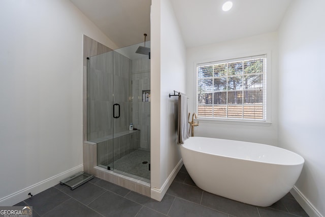 bathroom with a freestanding tub, a stall shower, tile patterned flooring, and baseboards