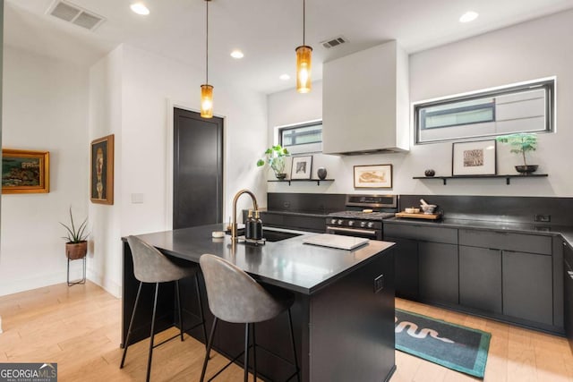 kitchen with visible vents, dark countertops, a sink, and stainless steel stove