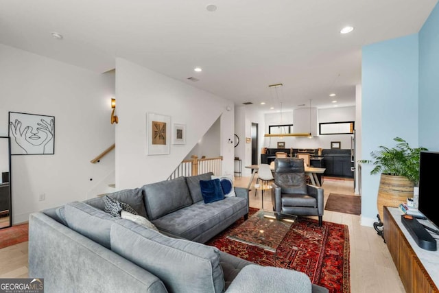 living area with baseboards, light wood finished floors, stairway, and recessed lighting