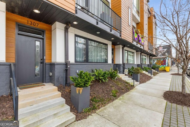 entrance to property featuring a balcony and brick siding