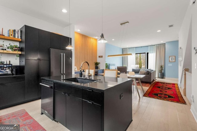 kitchen featuring modern cabinets, high end refrigerator, a sink, and dark cabinets