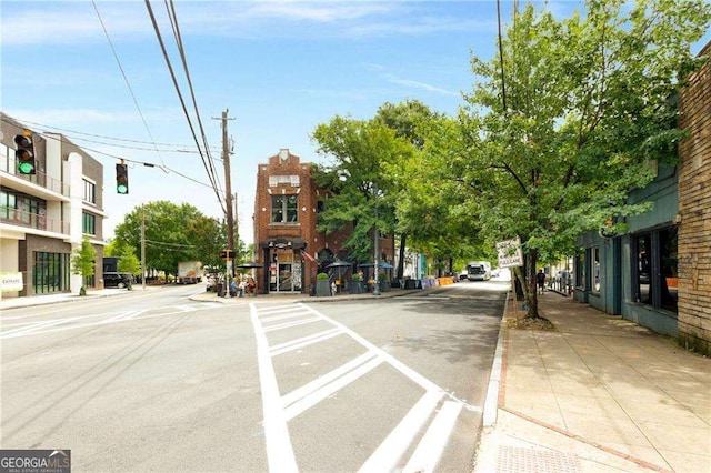 view of street featuring street lights, curbs, traffic lights, and sidewalks