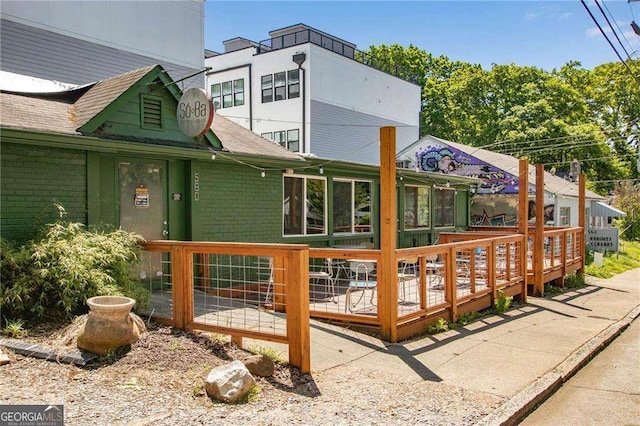 back of house featuring brick siding and a wooden deck