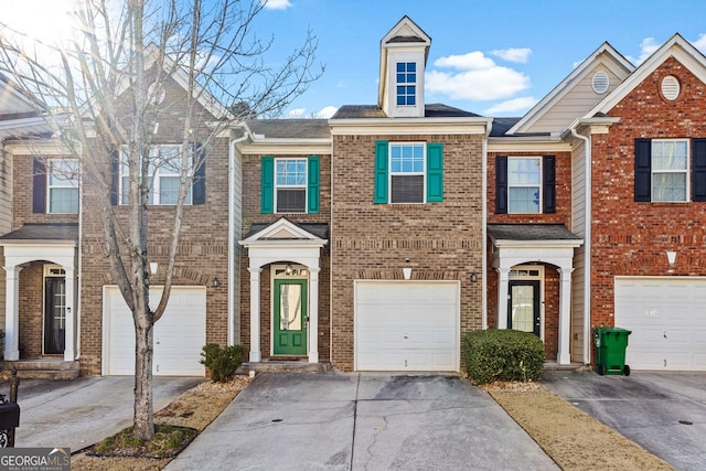 multi unit property with driveway, an attached garage, and brick siding