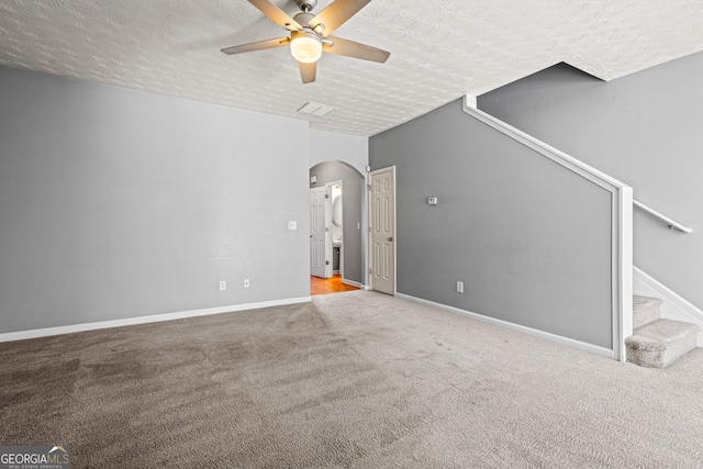 interior space featuring arched walkways, a textured ceiling, baseboards, and stairs