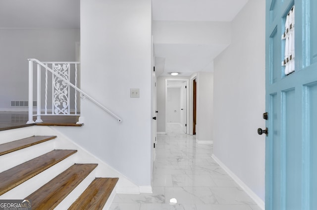 stairs with marble finish floor, visible vents, and baseboards