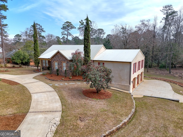 view of front of house featuring metal roof, stone siding, a front yard, and stucco siding