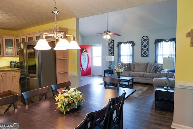 dining room with a textured ceiling, a ceiling fan, vaulted ceiling, and dark wood-style flooring