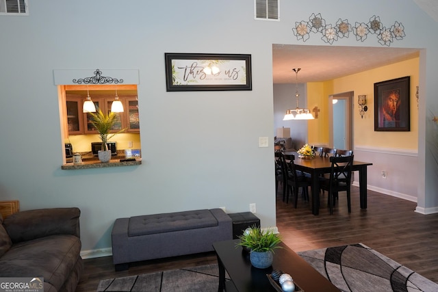 living room with a chandelier, visible vents, baseboards, and wood finished floors